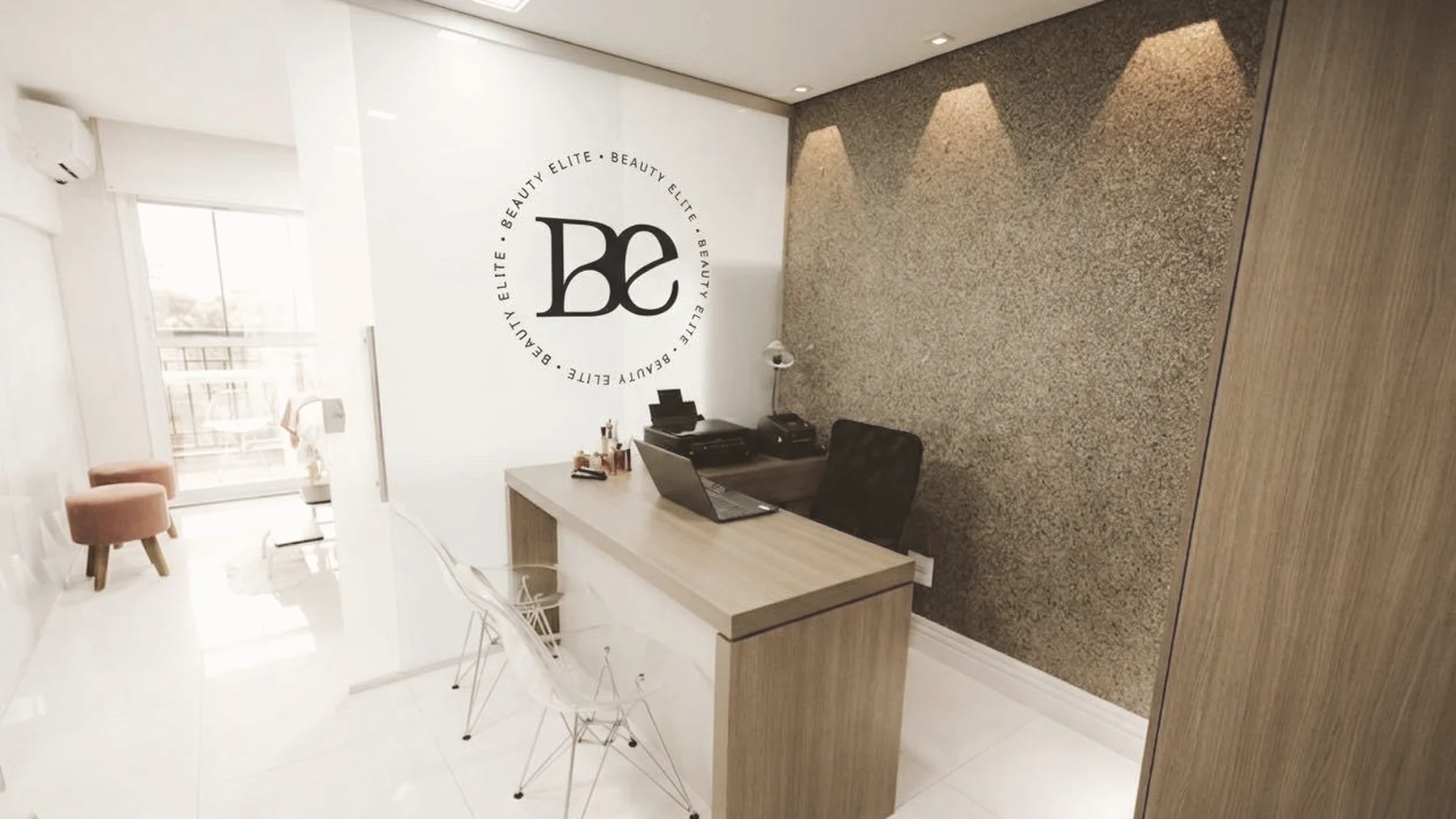 Recepção da Beauty Elite, com bancada de madeira clara e o selo da marca na parede